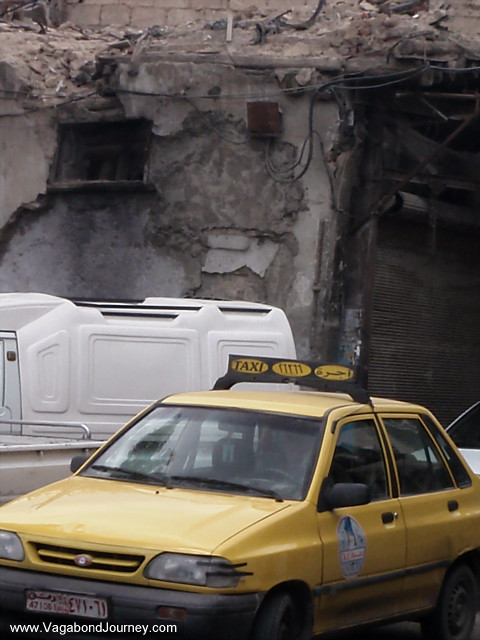 taxi in front of disintegrating building damascus